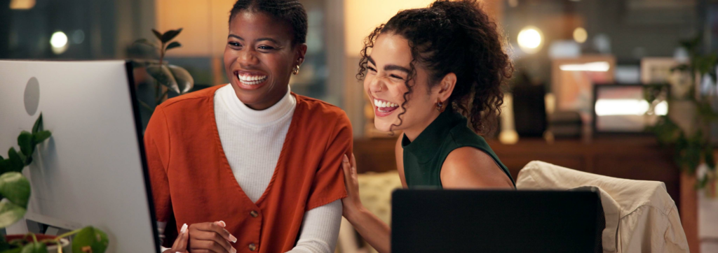 two colleagues laughing while working together at computer
