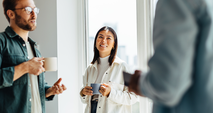 colleagues having coffee and talking in office

